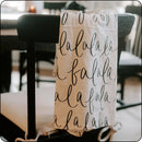 Christmas tea towel with 'Fa La La' design draped over a chair for a cozy holiday touch
