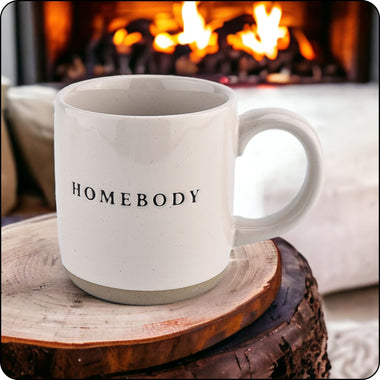 Homebody stoneware mug resting on a wood round near a cozy fireplace, perfect for warm drinks