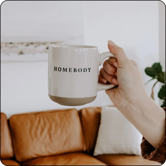 Person holding Homebody stoneware mug with a leather couch in the background, ideal for relaxed moments