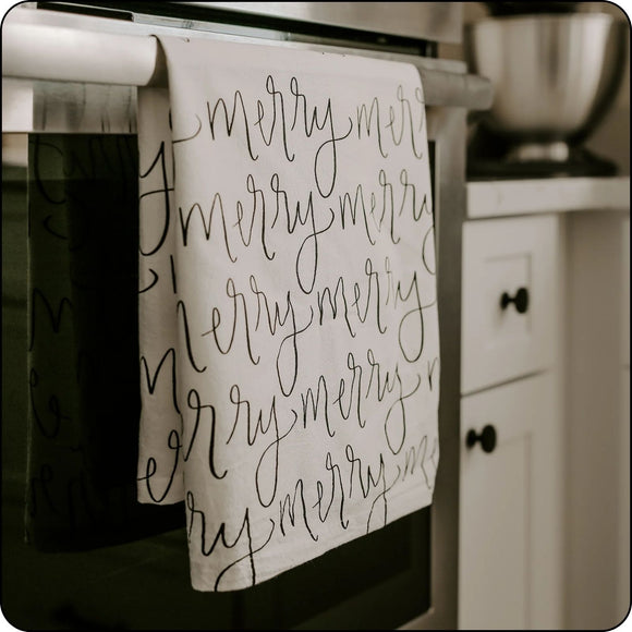 Festive Merry Christmas tea towel hanging on oven handles, perfect for holiday kitchen decor