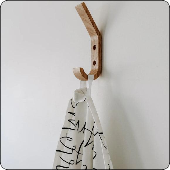 Cotton Christmas tea towel with script wording, hanging on a kitchen hook